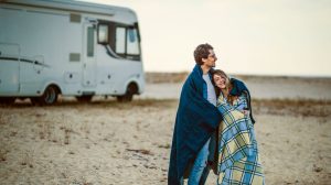 man and woman wrapped in blankets with RV in background