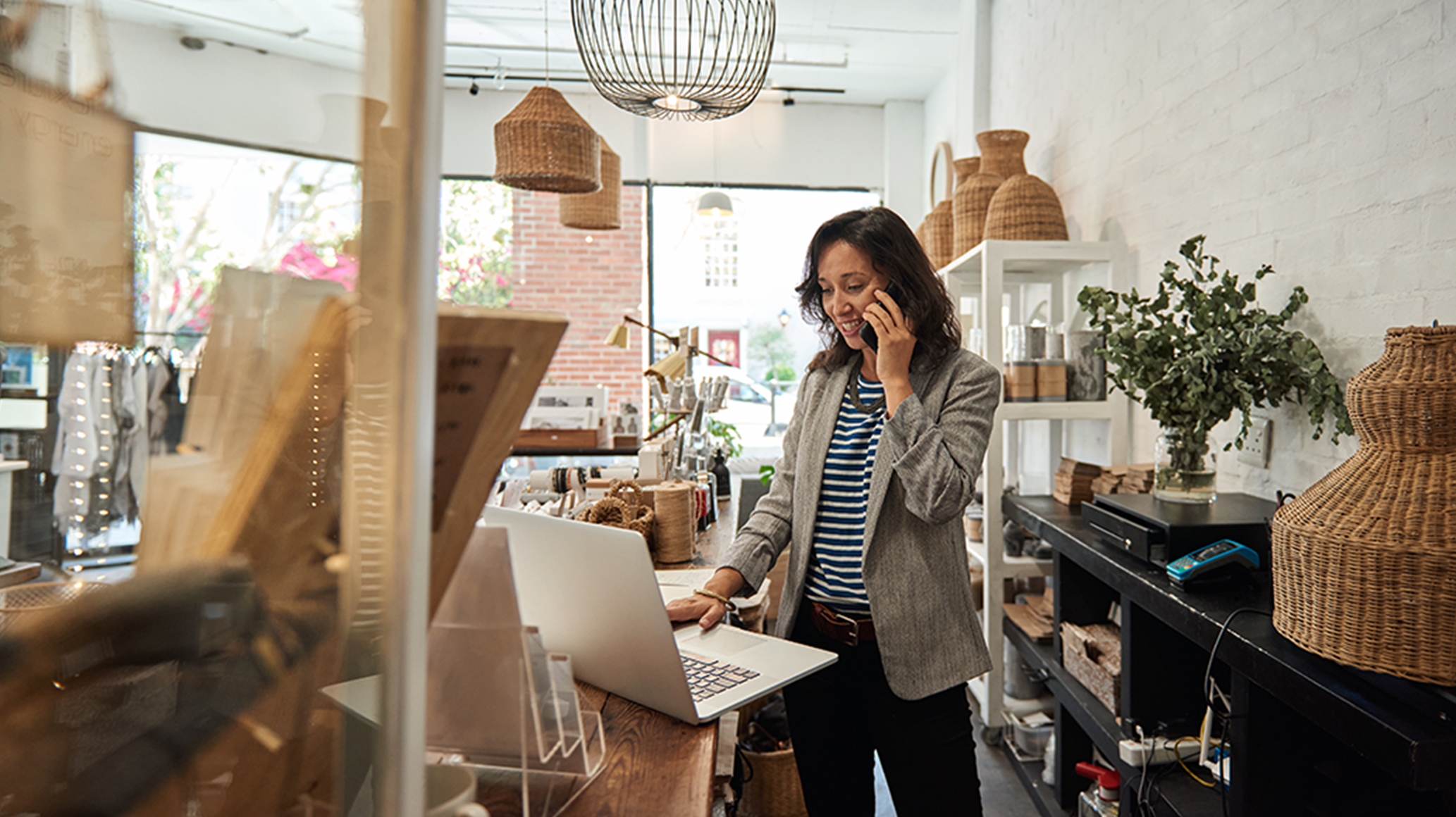 Businesswoman on phone and laptop in retail shop