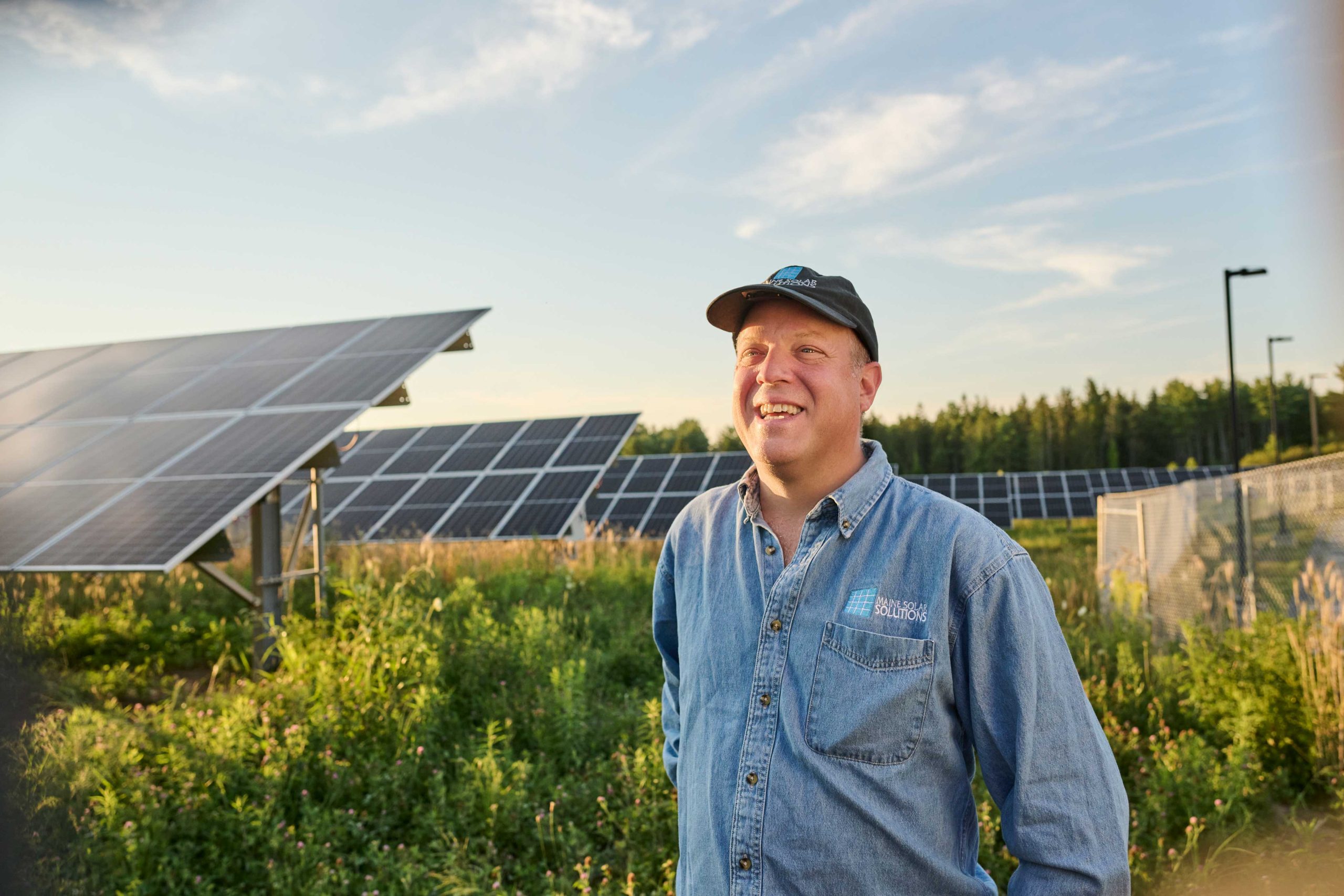 Man standing in front of solar farm with a big smile.