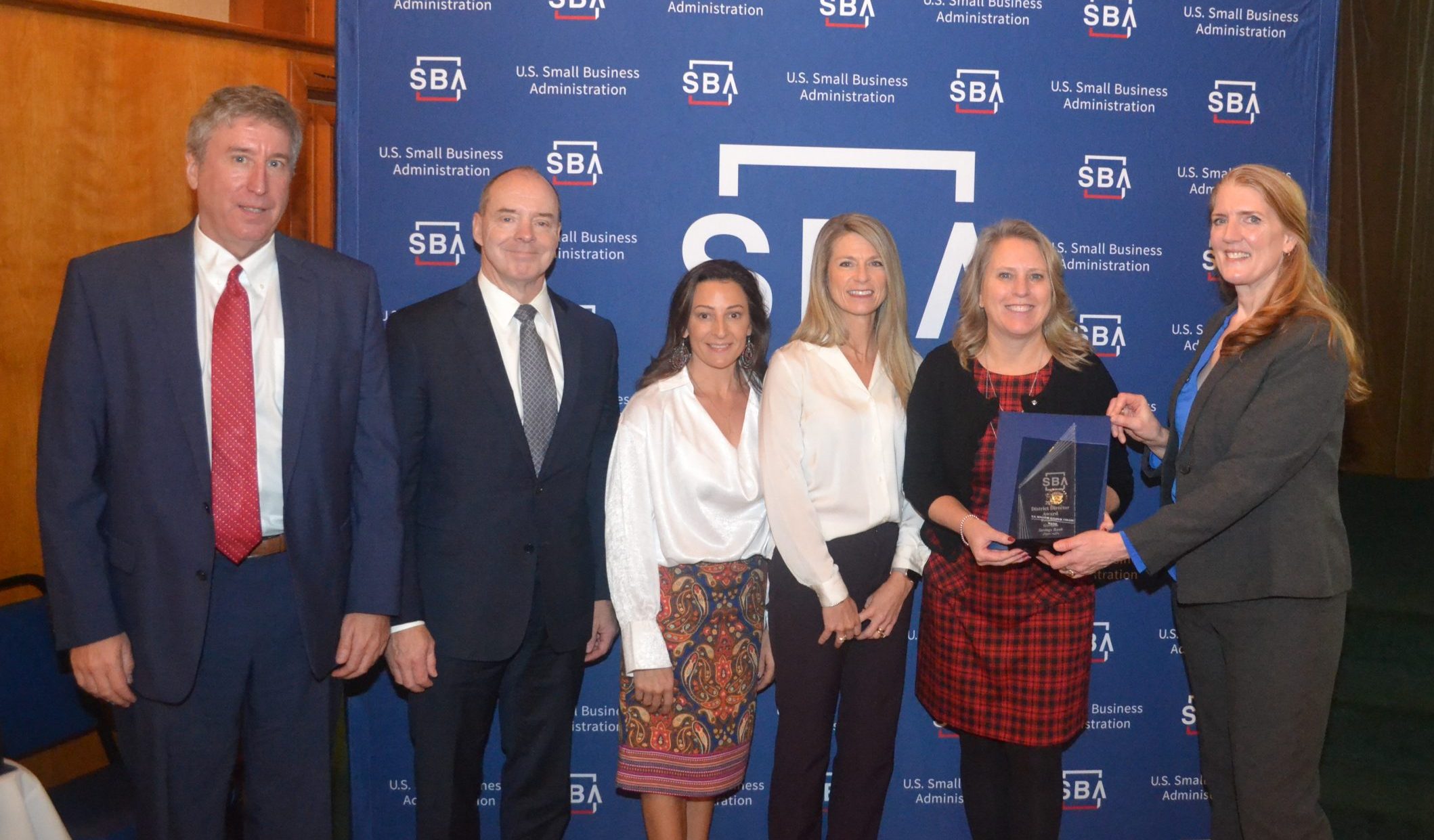 Six people standing in front of the SBA backdrop receiving an award.